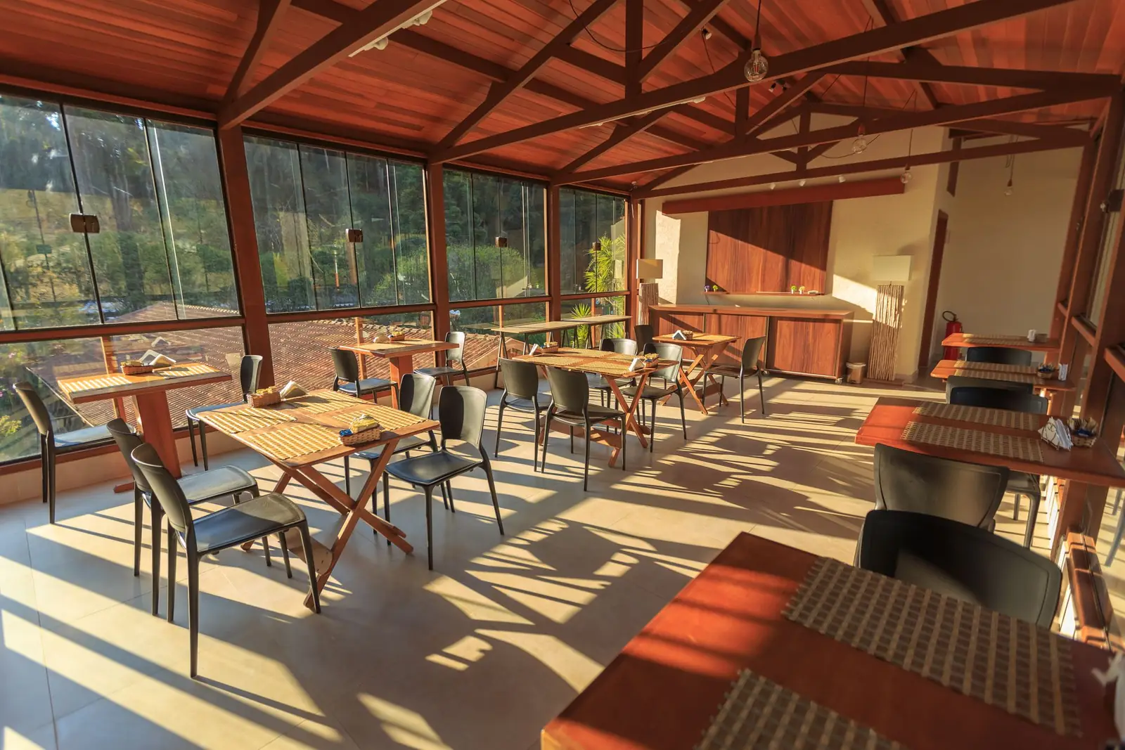 A wood-beamed dining room with late-afternoon sun across the tables